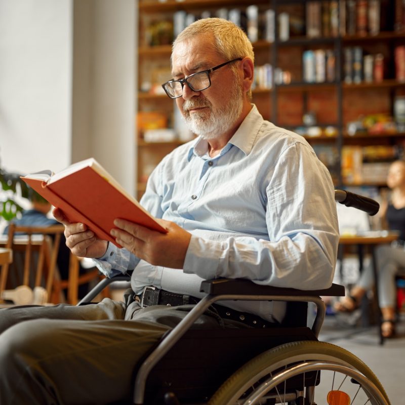 Homme en fauteuil roulant lisant un livre